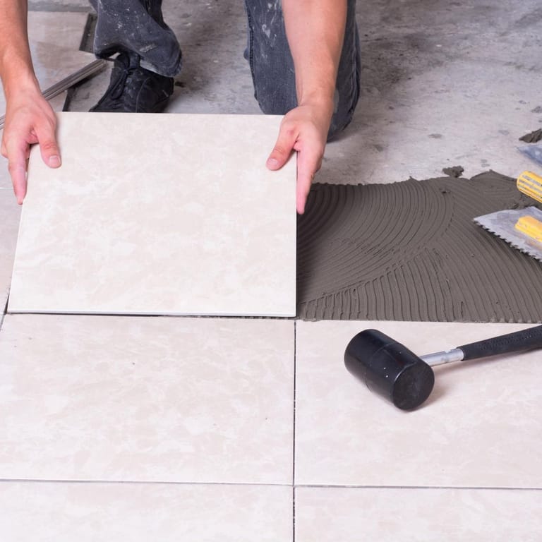 A person is laying a tile on the floor.